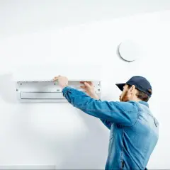 Technik sprawdza klimatyzator, by obniżyć miesięczny koszt klimatyzacji.