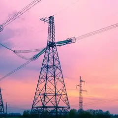 Wieże energetyczne na tle różowego nieba. Linie wysokiego napięcia, które niosą prąd o określonej częstotliwości, tworzą malowniczy krajobraz.