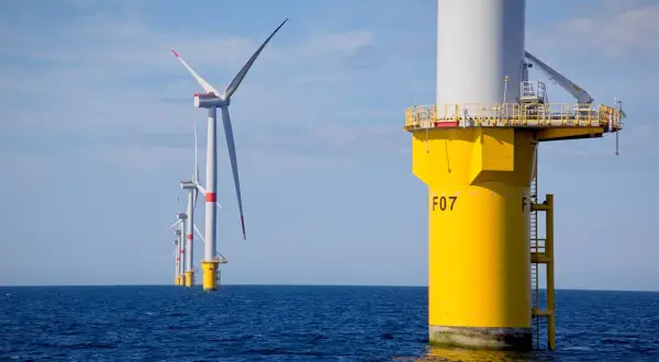 Wielkie turbiny wiatrowe na Bałtyku, symbolizujące **baltic power**, generują czystą energię na tle błękitnego nieba.