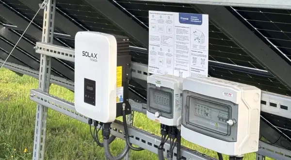 Falownik Solax Power i skrzynki przyłączeniowe na tle paneli PV. Zastanawiasz się, ile kosztuje wymiana falownika? Sprawdź instrukcje i kontakty.